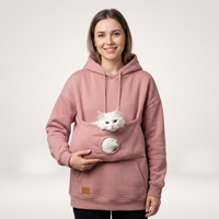 Frau im rosa Hoodie mit Kuscheltasche, eine weiße Katze schaut heraus